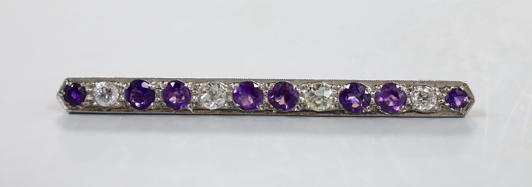 A white metal, eight stone amethyst and four stone diamond set bar brooch, 57mm, gross weight 4.6 grams.